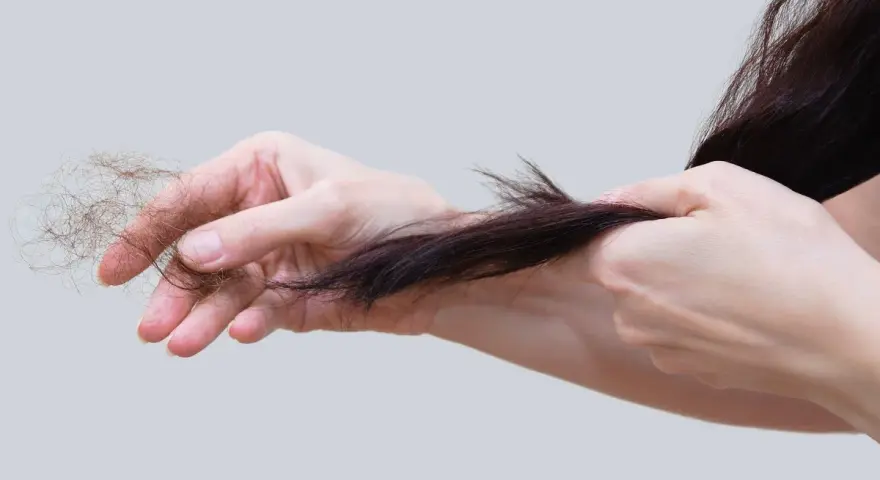 Mani che mostrano perdita capelli allattamento, cercando rimedi naturali per rinforzare i capelli indeboliti.