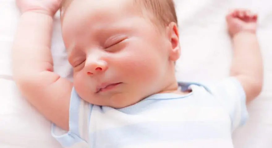 Un neonato dorme sereno con le braccia alzate. Sembra che i neonati possano mangiare mentre dormono, un vero miracolo della natura.