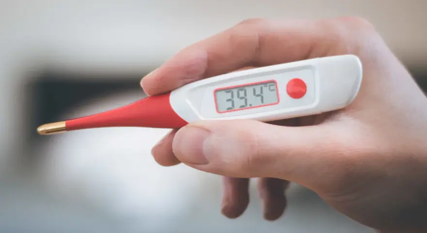 Termometro digitale mostra 39.4°C. Febbre alta, serve antibiotico e tachipirina.