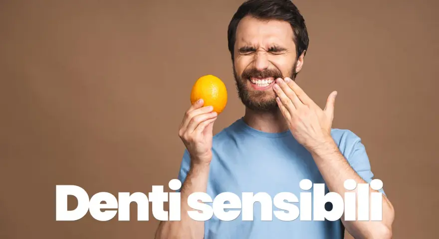 Uomo con espressione sofferente, tiene un'arancia e si tocca la guancia, mostrando i suoi denti sensibili al freddo.