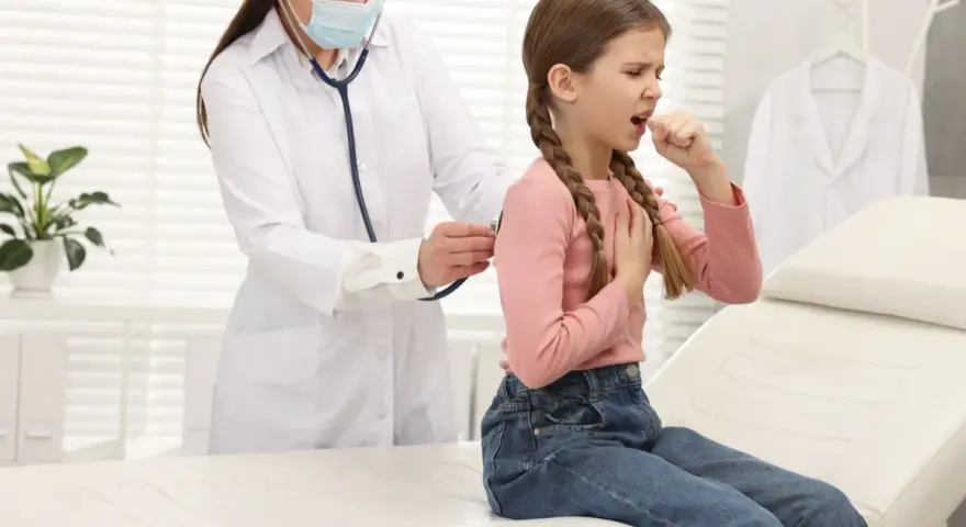 Bambina con tosse, uno dei sintomi della pertosse, visitata dal medico.