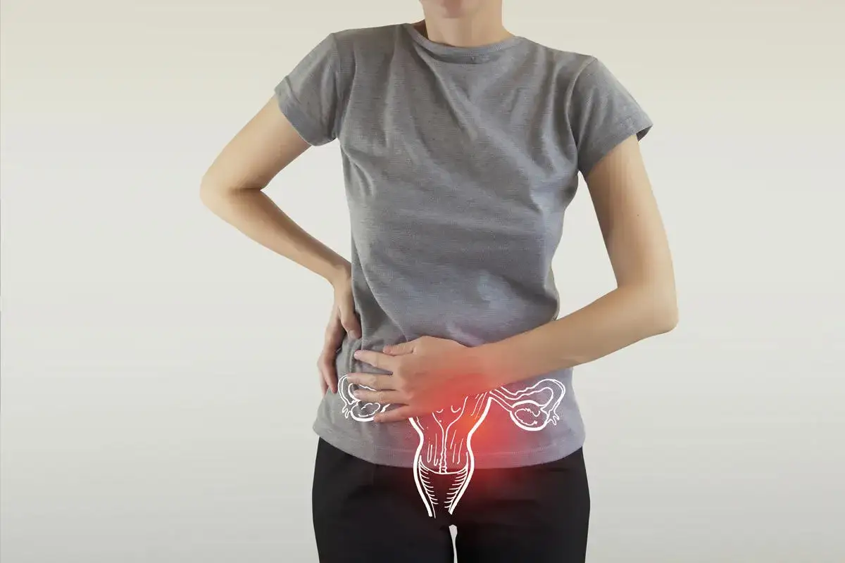 Donna con mani sull'addome, evidenziando dolore e gonfiore. L'ovulazione dolorosa e la pancia gonfia sono rappresentate da un disegno stilizzato dell'utero.