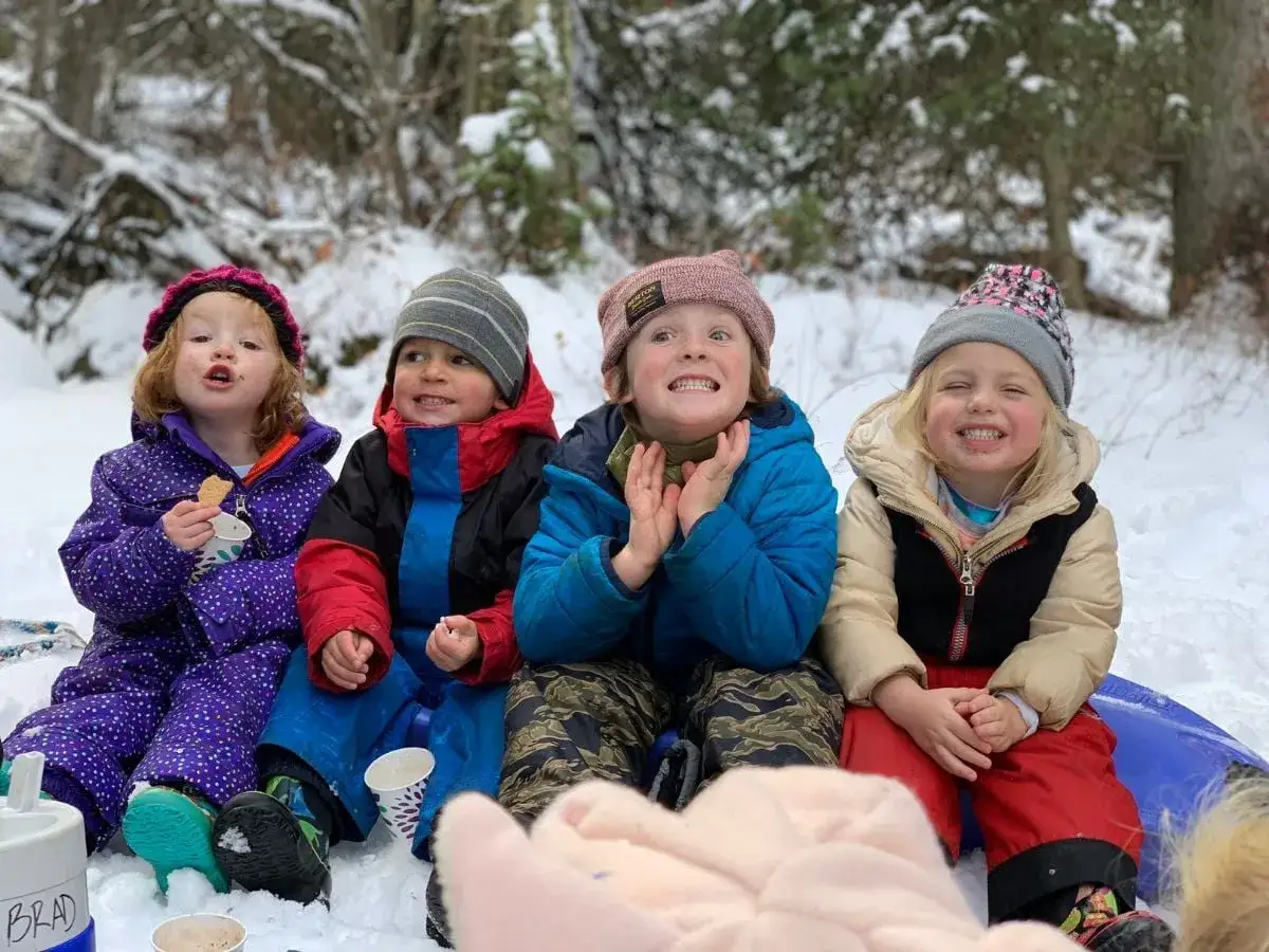 Bambini felici nella neve, un esempio di come vestire i bambini in questo periodo: tute calde, cappelli e guanti per giocare all'aperto.