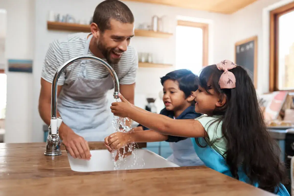 Padre insegna ai figli a lavarsi le mani per prevenire il contagio. Mani pulite, bocca protetta, piedi sani. I genitori insegnano l'igiene.