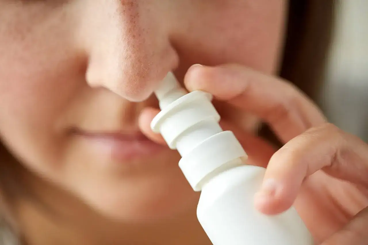 Persona usa uno spray nasale, un rimedio per la sinusite.