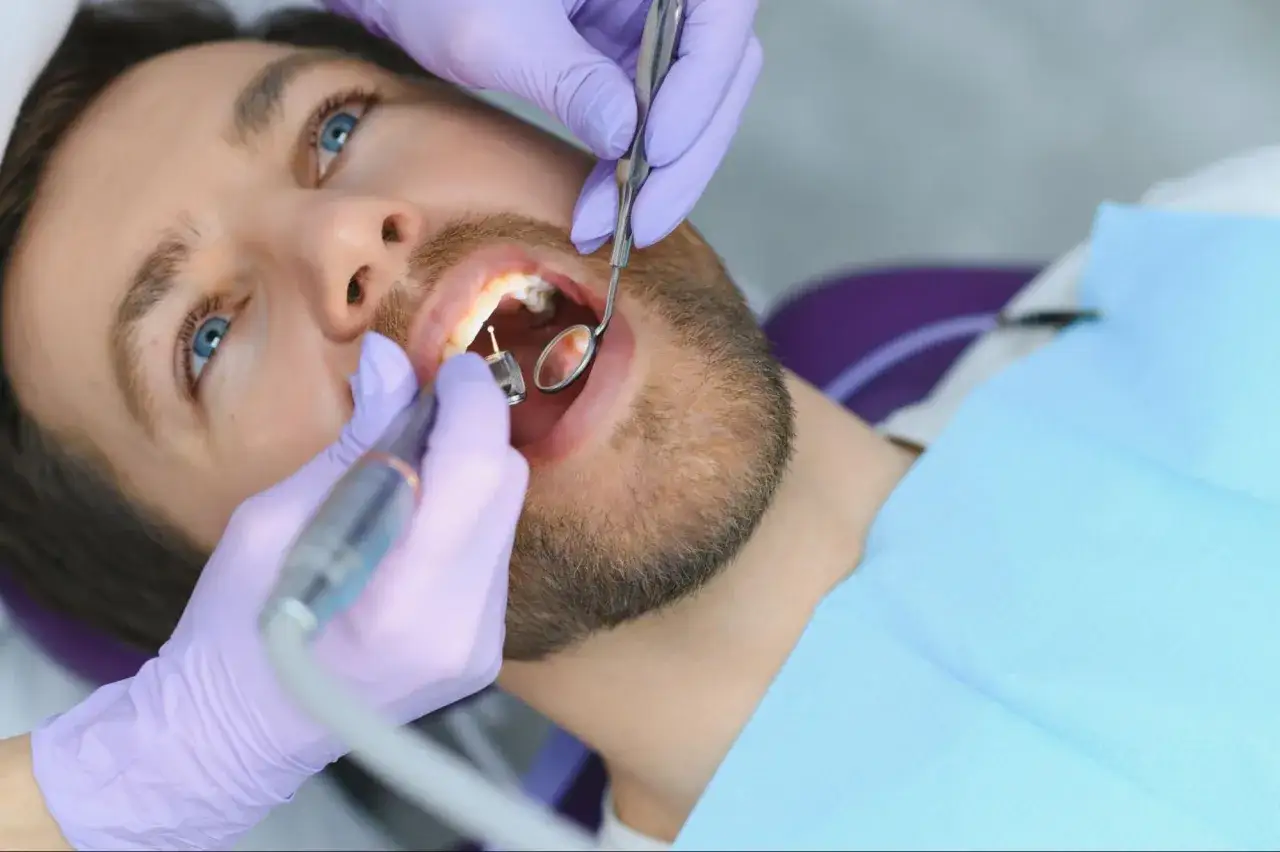 Un dentista esegue un'otturazione dente su un paziente con occhi azzurri.