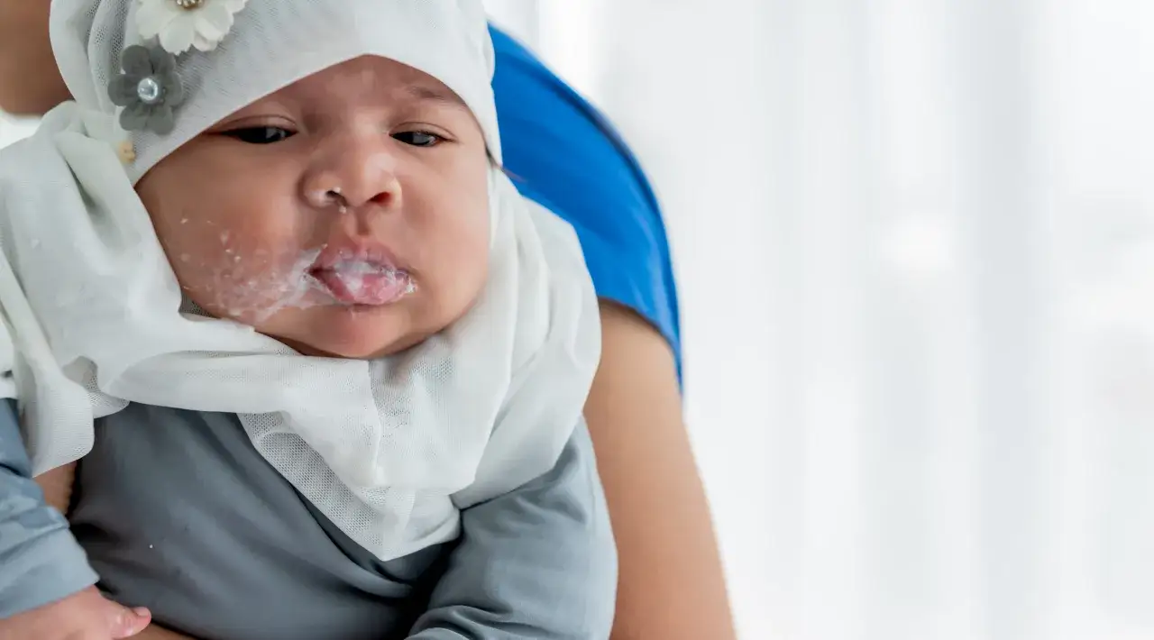 Bambino con latte sulle labbra e sul viso, un segno per capire se un neonato ha il reflusso.