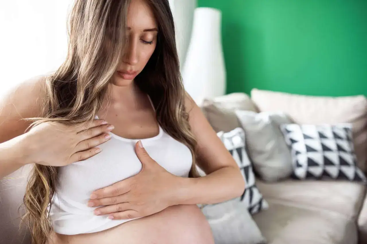 Donna incinta con mani sul seno, sollevata dal dolore al seno scomparso inizio gravidanza.