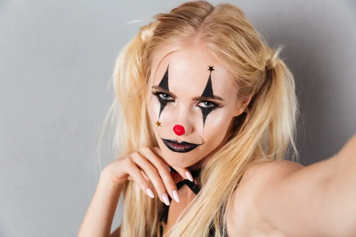 Ragazza con trucco da clown, idee per trucchi carnevale facili e veloci. Naso rosso, stelle e bocca nera.