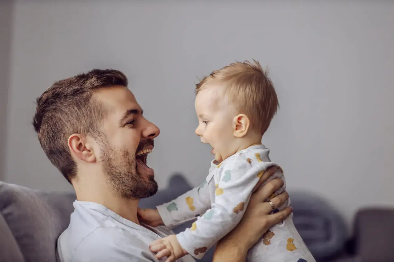 Padre e figlio si guardano con gioia, un momento perfetto per capire come stimolare un bambino a parlare con giochi e interazione.