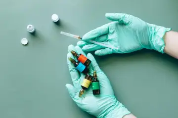 Mani guantate preparano fiale colorate, una siringa in mano, forse per il rocefin principio attivo.