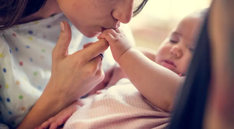Dolce bacio di una madre al suo neonato. La protezione e l'amore per i neonati sono fondamentali, soprattutto contro malattie come la pertosse.